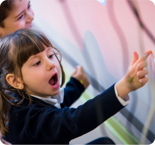 An early primary student excitedly points to a screen.